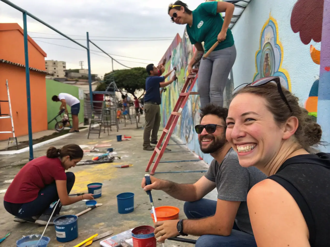 A photograph of a community outreach program in action, showing volunteers and participants working together on an art project. The image conveys a sense of collaboration, creativity, and community spirit.